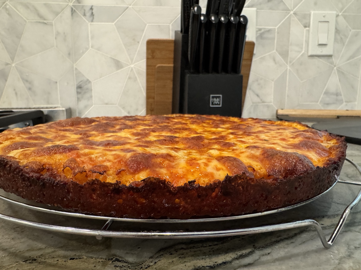Greg’s deeply browned pan pizza cooling on a rack in his kitchen